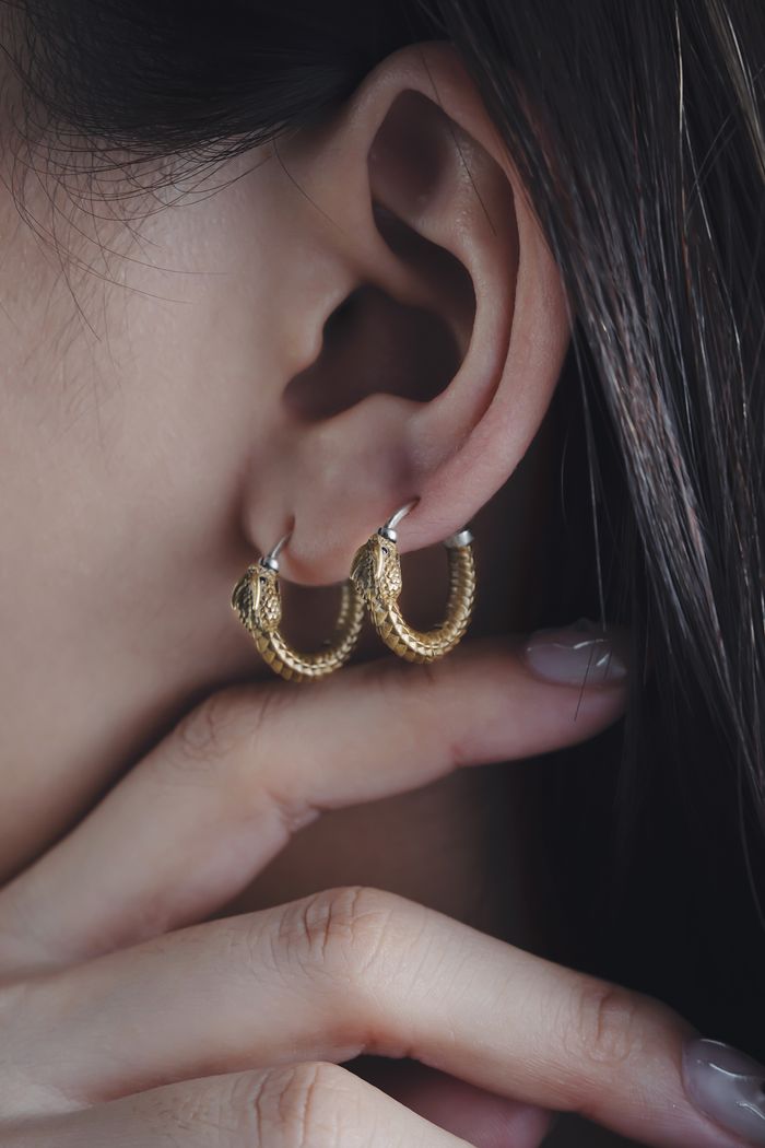 Elegant gold hoop earrings on a woman's ear with a focus on minimalist design and style.